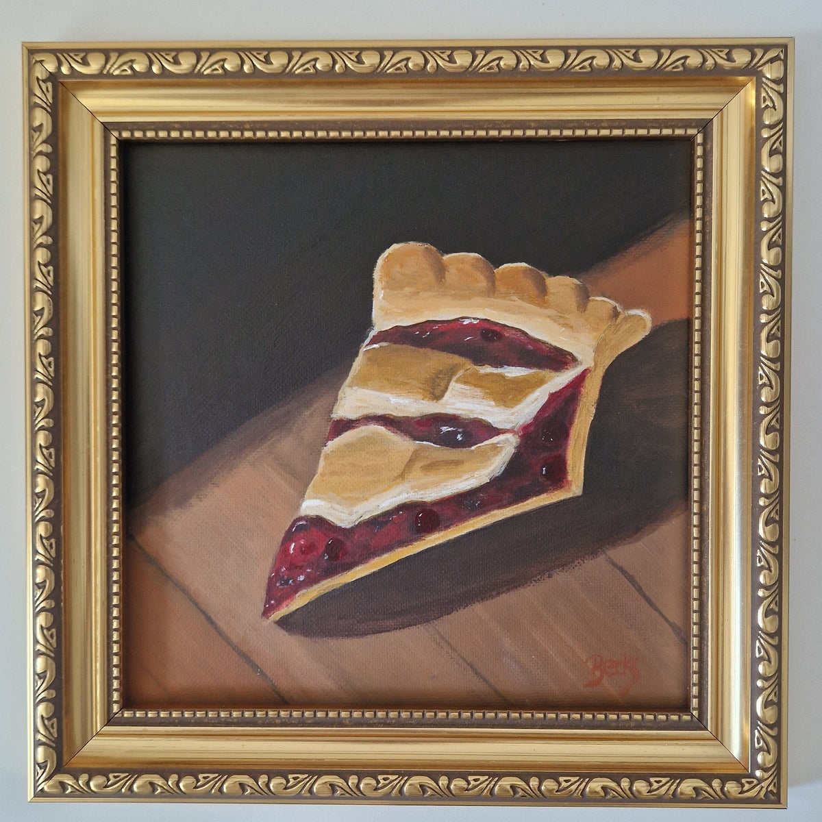 A framed painting of a single slice of pie on a wooden surface against a dark background, enclosed in an ornate gold frame.